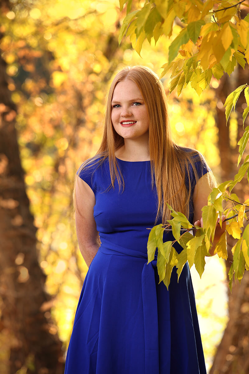 Warm woman senior high school graduate glowing leaves fall autumn Yellow blue dress Idaho Photographer